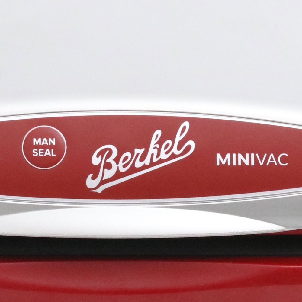 Nahaufnahme einer Berkel Minivac, kleine Vakuummaschine, mit Hervorhebung des Markenlogos und der Worte "MAN SEAL" und "MINIVAC" auf der rot-weißen Platte.