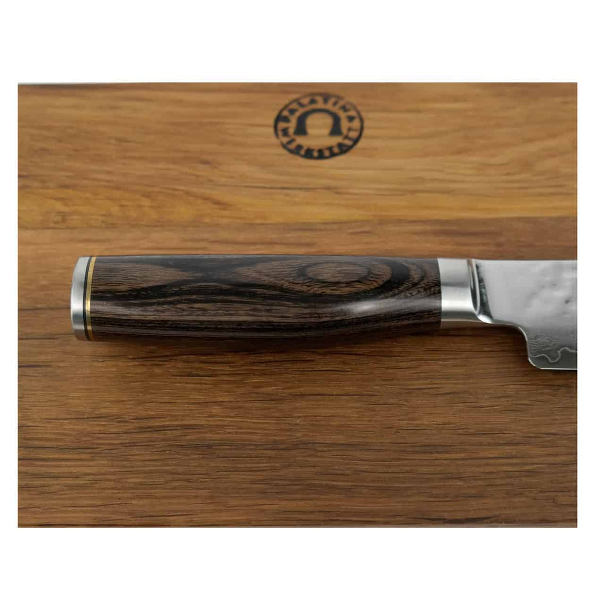 Eine Nahaufnahme des hochwertigen, ultrascharfen japanischen Messers Kai Shun Premier Tim Mälzer TDM-1704, eines Schinkenmessers aus Damaststahl, das auf einem massiven, 30 x 18 cm großen Schneidebrett aus Fassholz ruht. Das Messer hat einen polierten, dunklen Holzgriff mit aufwendiger Maserung und einen glänzenden Metallkropf, während das Schneidebrett auf seiner Oberfläche ein eingraviertes Logo aufweist.
