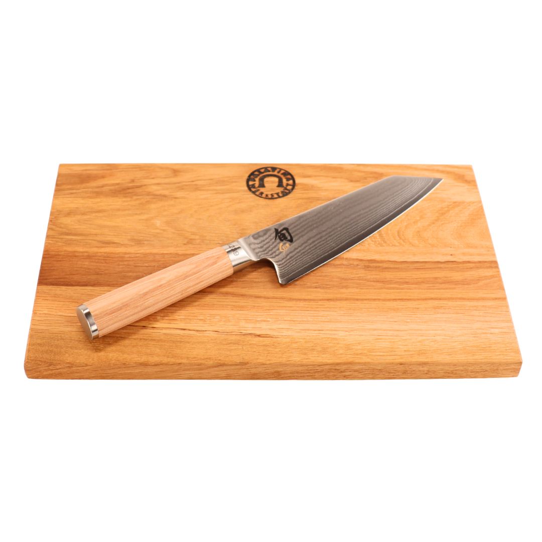 Das Kai Shun Classic White Kiritsuke - Limitierte Edition (5.555 St.) mit Holzgriff wird auf einem Schneidebrett aus Eiche mit natürlicher Holzmaserung und einem Logo in der oberen Mitte präsentiert.