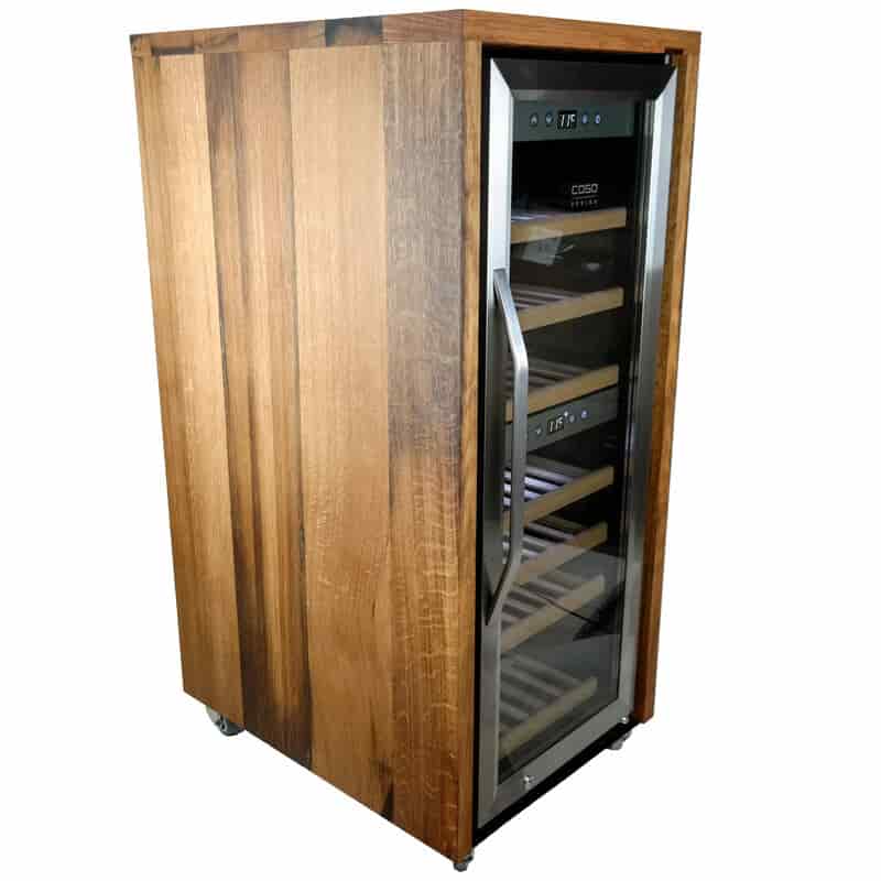 Der Weinkühlschrank 2 Zonen CASO WineComfort 38 Unikat aus Holz von alten Weinfässern (Eiche) ist ein einzigartiger Weinkühlschrank aus alten Eichenweinfässern mit einer Glastür, durch die man die Innenregale sehen kann. Das Gerät verfügt über eine digitale Temperaturanzeige an der Oberseite und ist an der Vorderseite mit einem eleganten Metallgriff versehen. Das Äußere aus wiederverwendetem Holz hat eine glatte Oberfläche und der Kühlschrank steht auf kleinen Rädern und bietet Zweizonen-Kühlfunktionen.