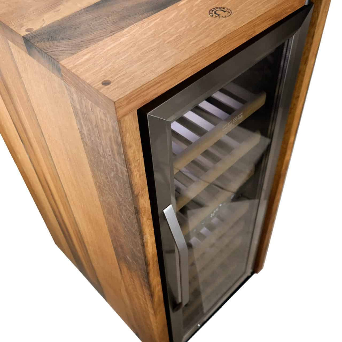 Ein Weinkühler aus Holz mit Glastür und Metallgriff. Im Inneren befinden sich mehrere horizontale Regale zur Aufbewahrung von Flaschen. Das Holz weist eine Mischung aus hellen und dunklen Maserungen auf. In der oberen rechten Ecke des Kühlers ist ein kleines rundes Logo zu sehen.