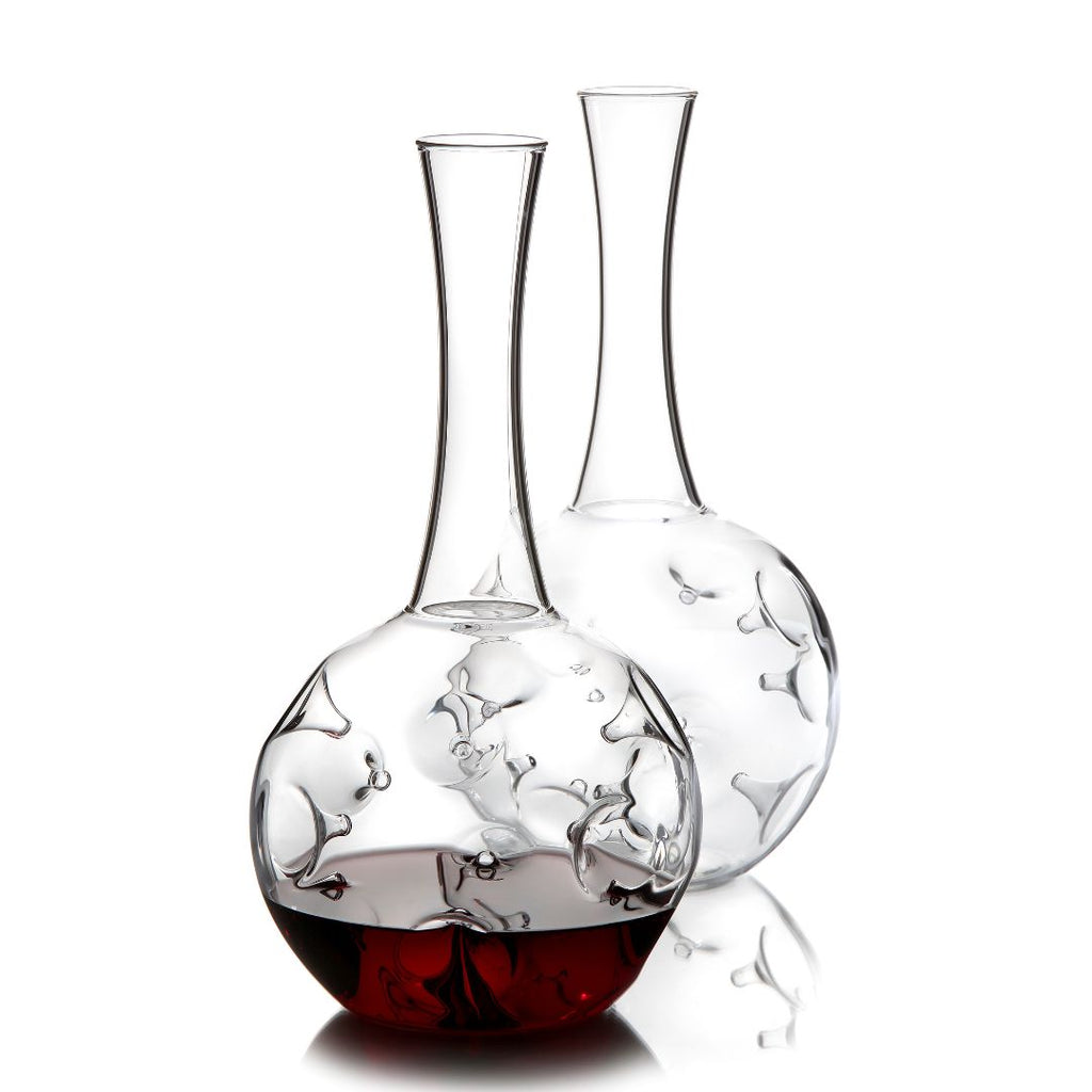 Der Weindekanter "Eddy" - 1,5L Karaffe aus Borosilikatglas von Zieher präsentiert ein innovatives Design mit schmalem Hals und rundem Boden; eine ist mit Rotwein befüllt und zeigt ein edles Relief, die andere steht leer dahinter.