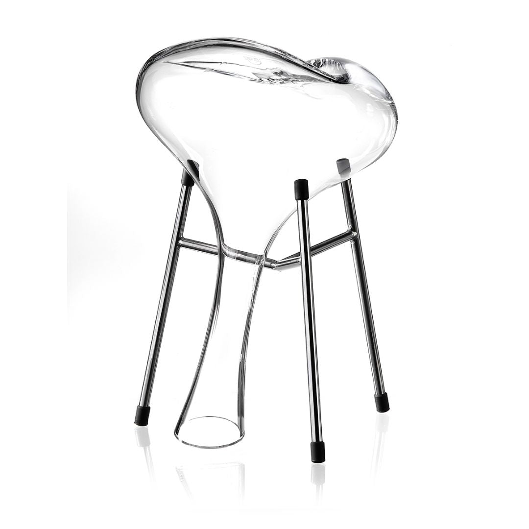 Ein moderner Stuhl mit einer klaren Sitzfläche, inspiriert von dem Dekanter Pebble von Zieher aus Kristallglas - 1,8 L Handarbeit, glänzenden Metallbeinen und schwarzen Gummifüßen. Die Sitzfläche weist in der Mitte eine markante trichterförmige Erweiterung auf einem schlichten weißen Hintergrund auf.