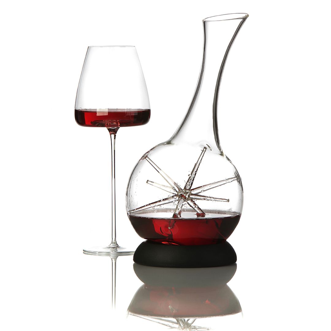 Ein Glas Rotwein steht neben dem Weindekanter "Star" - Exklusive Karaffe mit Sternendesign (34 cm, Zieher), beide elegant auf einer spiegelnden Fläche platziert.