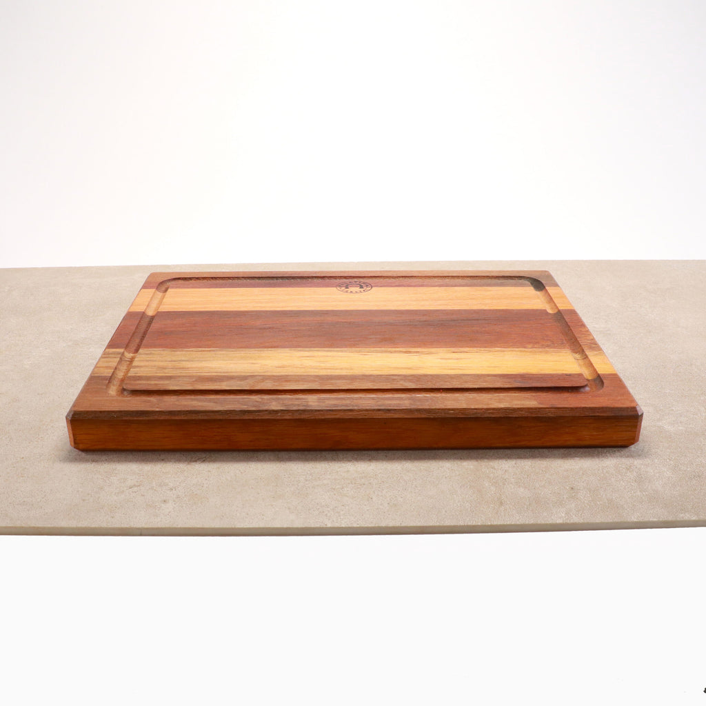 Ein Palatina Küchenbrett mit Saftrille 40x30 cm aus Weinfassholz, das verschiedene Brauntöne aufweist, liegt auf einer hellen Oberfläche. Das Schneidebrett hat an den Rändern eine geschnitzte Saftrille, um Saft aufzufangen. Der schlichte weiße Hintergrund hebt die Holzmaserung und -struktur des Bretts wunderschön hervor.
