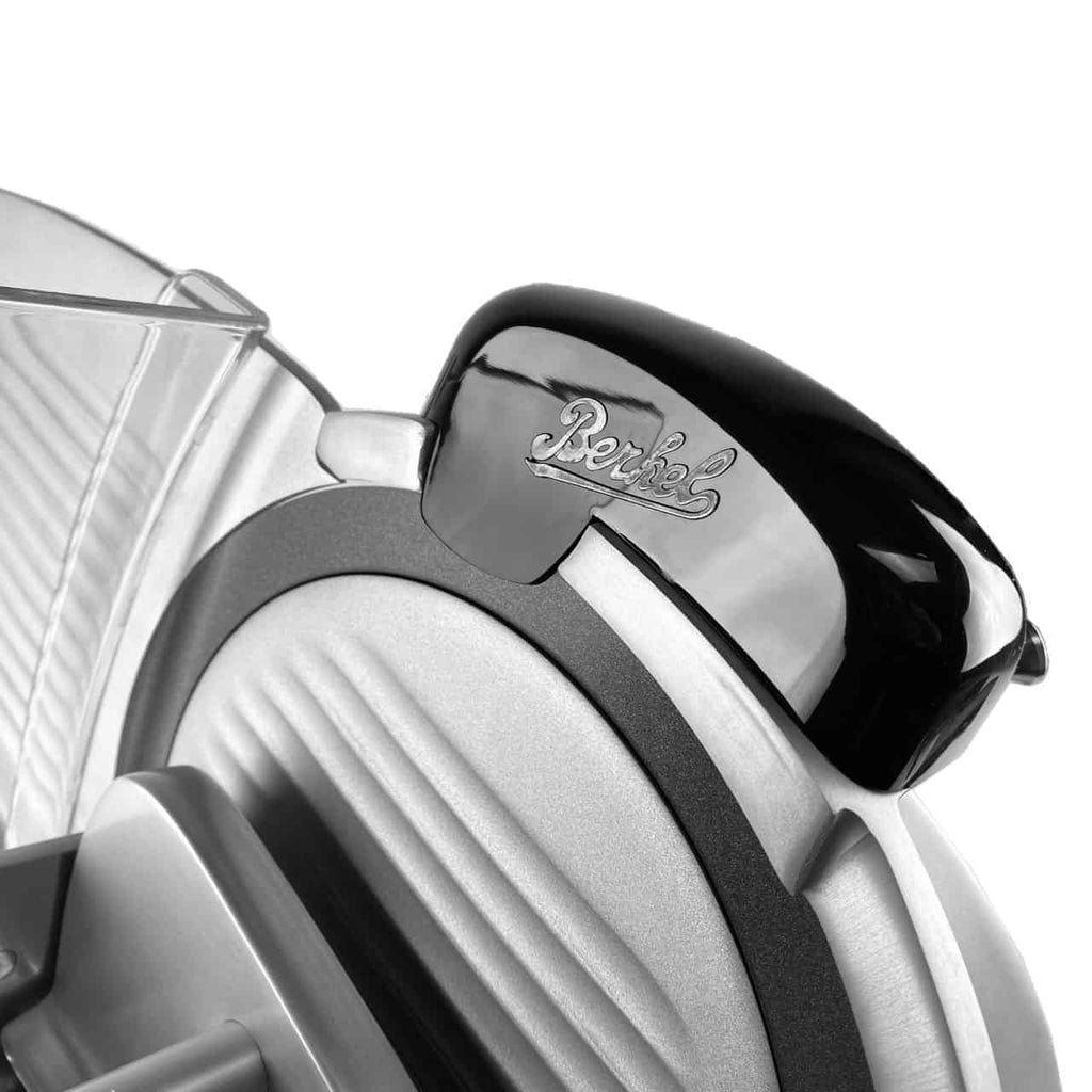 Nahaufnahme eines eleganten, modernen Küchengeräts mit schwarzer und metallisch-silberner Oberfläche und dem Markenlogo von Berkel Red Line auf einer schwarzen Abdeckung. Die Original Profi-Aufschnittmaschine Berkel Red Line 250 Grau Teflon sieht aus wie ein Allesschneider mit geriffelten Details und einem Schutzgitter und verfügt über einen beeindruckenden Messerdurchmesser von 25 cm.