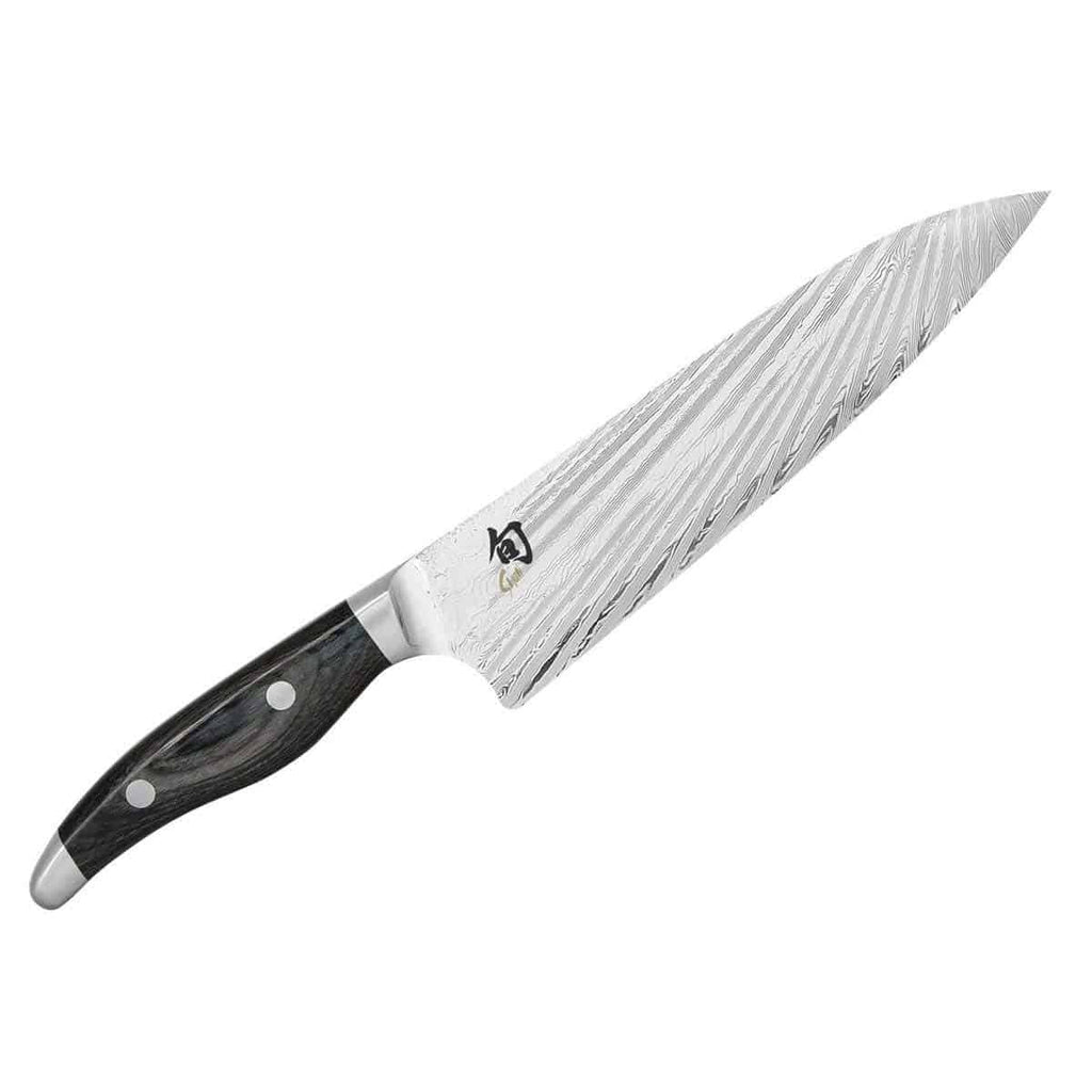 Wir präsentieren das Kai Shun Nagare NDC-0706 Kochmesser, ein hochwertiges Kochmesser mit einem schlanken, dunklen Griff mit zwei Nieten und einer 20 cm langen Klinge aus Damaststahl mit markanten Wellenmustern. Die Klinge zeigt stolz ein japanisches Kanji-Logo. Begleitet von einem basaltgrauen Schneidebrett aus Eiche mit den Maßen 34 x 21 cm.