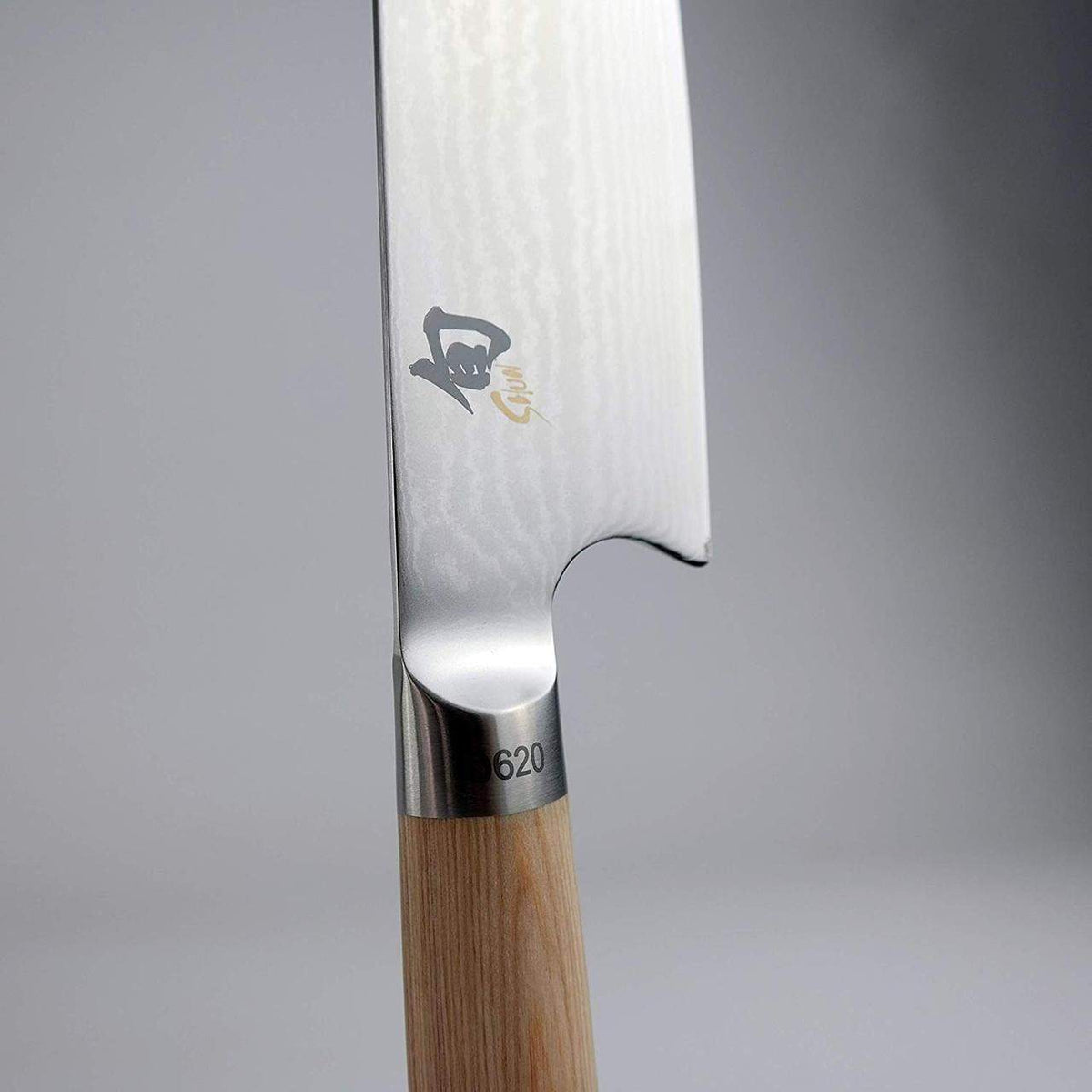 Nahaufnahme eines Kiritsuke-Messers in limitierter Auflage Kai Shun Classic White DM 0777W mit polierter Metallklinge. Das Messer weist ein japanisches Schriftzeichen und eine Marke in der Nähe der Klinge auf und hat einen Holzgriff mit der Nummer „620“ auf der Metallmanschette, wo die Klinge auf den Griff trifft. Der Hintergrund ist unscharf.