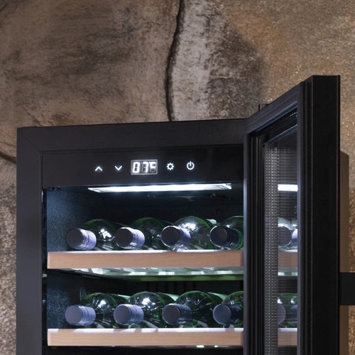 Ein eleganter, schwarzer Weinkühlschrank 2 Zonen CASO WineComfort 38 Schwarz mit leicht geöffneter Tür zeigt mehrere Flaschen Wein, ordentlich angeordnet auf Holzregalen. Die digitale Temperaturanzeige zeigt 8,75 Grad. Der Hintergrund zeigt eine raue, steinstrukturierte Wand, die die Zweizonenfähigkeit des Kühlschranks hervorhebt.
