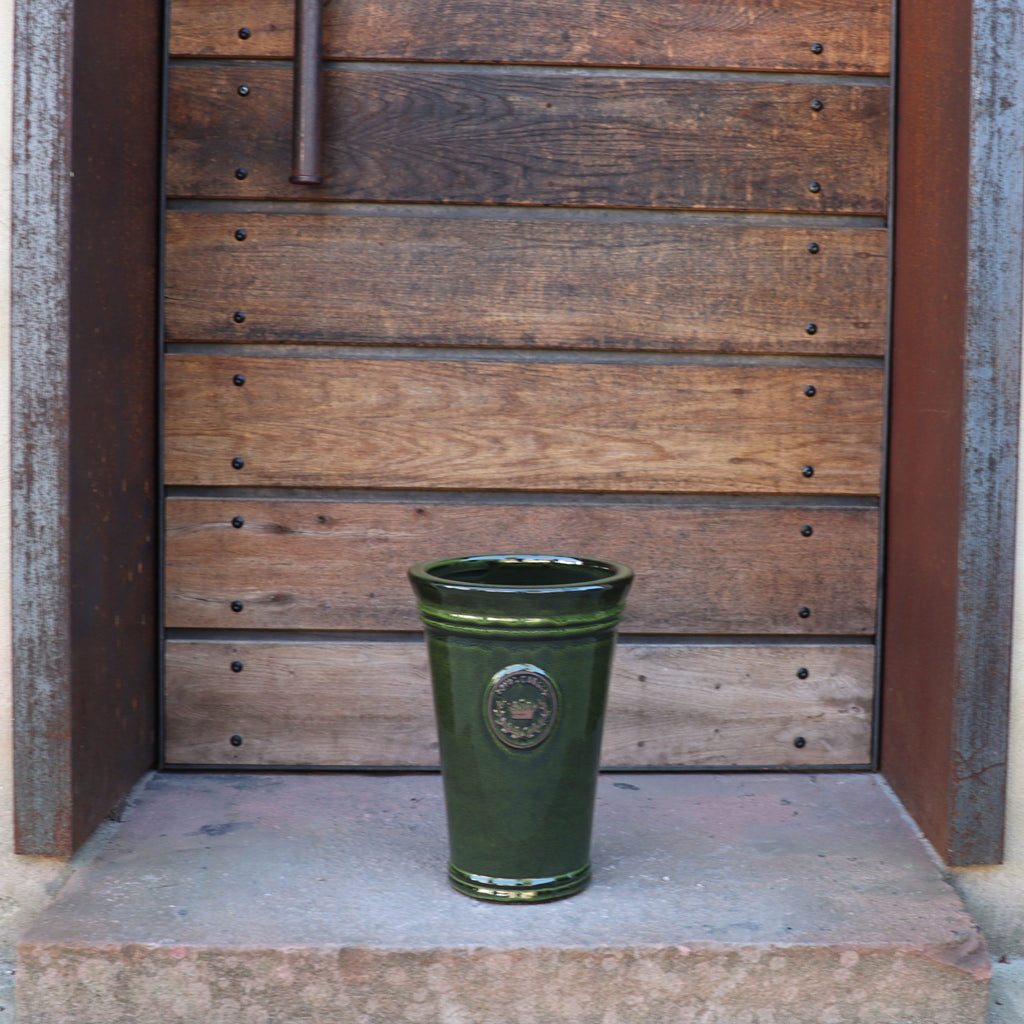Die Vasenform "Royal Garden Green" (33-51 cm) steht auf einer steinernen Türschwelle vor einer Holztür mit Metallakzenten und bringt rustikalen Azur-Provence-Charme in Ihren Eingangsbereich.