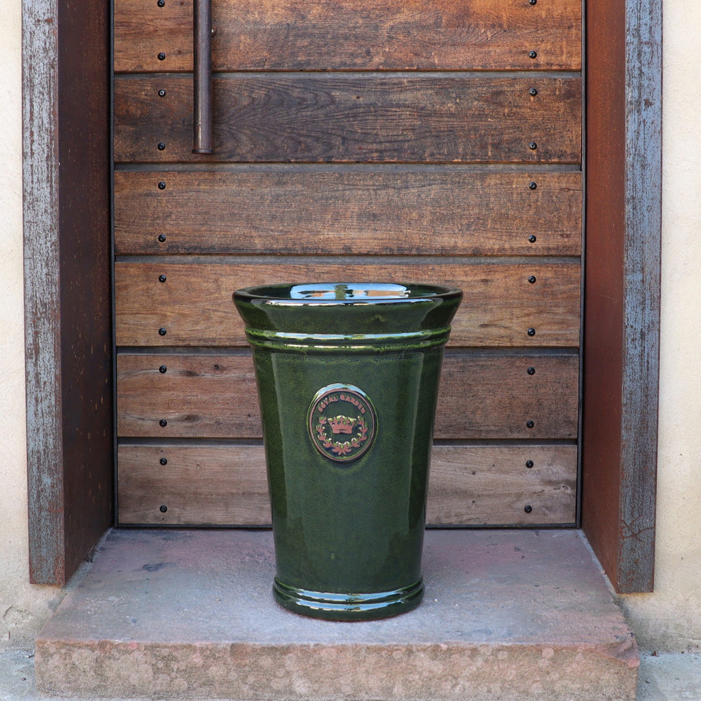 Die Vasenform "Royal Garden Green" (Höhe 33-51 cm), eine hohe, glänzend dunkelgrüne Keramikvase mit rundem Emblem, steht auf einer Steinstufe vor einer rustikalen Holztür mit Metallakzenten.