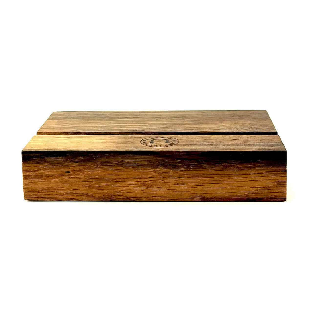 Eine geschlossene Holzbox mit einem einfachen, rechteckigen Design und natürlichen Maserungen ist ein markantes Merkmal. Die Box hat eine glatte Oberfläche und in der Mitte ist das Logo von Palatina Werkstatt eingebrannt. Dieser handgefertigte Tablethalter von Palatina Werkstatt steht vor einem schlichten weißen Hintergrund.
