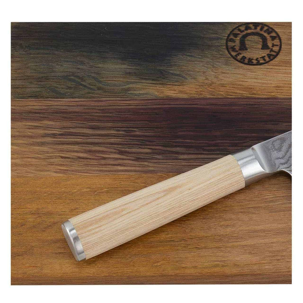 Eine Nahaufnahme eines hölzernen Schneidebretts mit mehrfarbigen Holzmaserungen, gefertigt aus einem Schneidebrett aus Weinfassholz 30x18 cm und einem teilweise sichtbaren Kai Shun Classic White DM-0700W Officemesser mit einer 9 cm langen Klinge, die diagonal über das Brett gelegt ist. Das Schneidebrett weist in der oberen rechten Ecke ein rundes Logo mit eingeprägtem Text und Design auf.