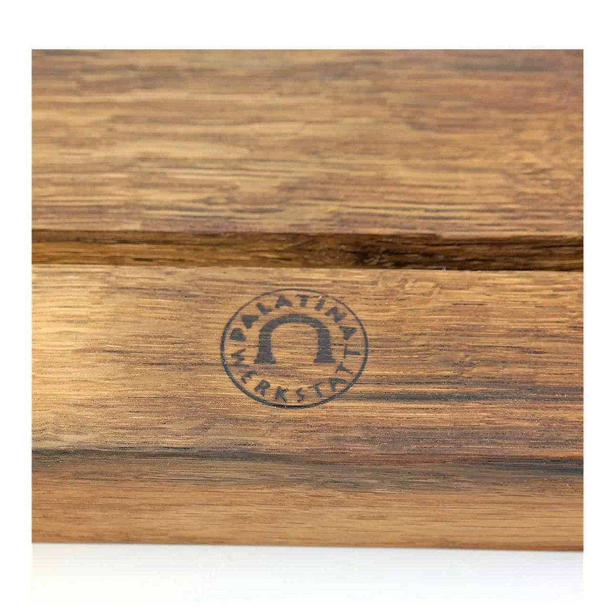 Nahaufnahme einer Holzoberfläche mit einem eingeprägten dunklen Logo. Das Logo hat eine auffällige Hufeisenform, umgeben von den Worten „Palatina Werkstatt“. Das Holz weist eine natürliche, rustikale Textur mit sichtbaren Maserungen auf und fängt den Charme dieses handgefertigten Tablethalters von Palatina Werkstatt perfekt ein.