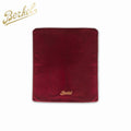 Die Berkel Abdeckhaube Cover + Poliertuch Home Line, Red Line, Volano in rotem Satin trägt den in Gold gestickten Markennamen „Berkel“ unten in der Mitte und zeigt das Berkel-Logo in Gold in der oberen linken Ecke des Bildes, wodurch Eleganz und Funktionalität nahtlos miteinander verbunden werden.
