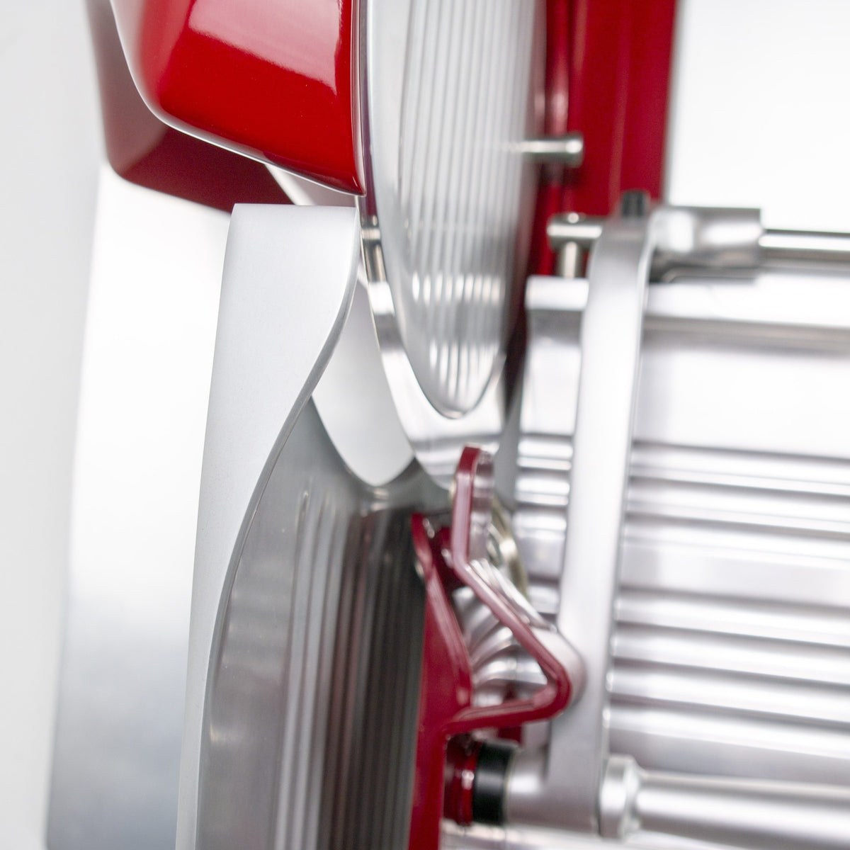 Nahaufnahme des Schleifaufsatzes für Berkel Aufschnittmaschine Home Line 200 oder 250 + Poliertuch, die die runde Klinge, den Sicherheitsschutz und den Verstellhebel zeigt, wobei die glatte Metalloberfläche und das moderne Design der Aufschnittmaschine hervorgehoben werden.