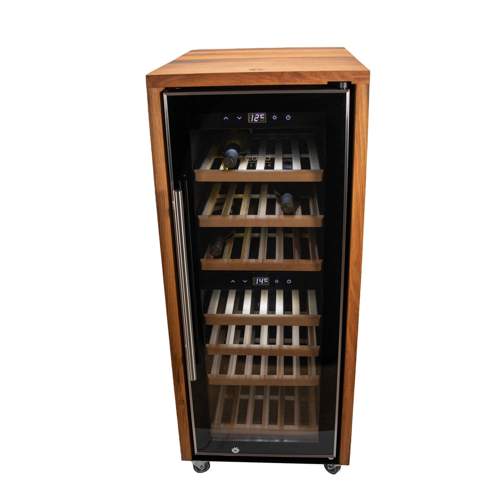 Der Weinkühlschrank 2 Zonen CASO WineComfort 38 in schwarz mit Fassholz-Umhausung verfügt über eine Glastür und eine digitale Temperaturanzeige an der Oberseite. Im Inneren lagern mehrere Flaschen Wein auf Holzlattenregalen. Der Kühler steht auf kleinen Rädern und lässt sich so leicht bewegen.