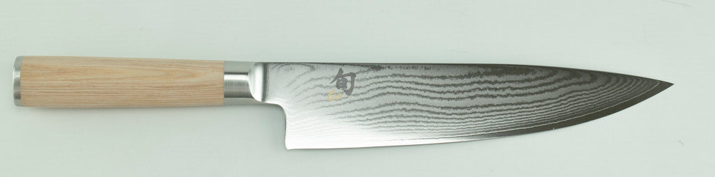 Das Kai Shun Classic White Kochmesser, DM-0706W, verfügt über eine gemusterte Stahlklinge mit einem markanten Wellendesign und einen hellen Holzgriff. Die 20 cm lange Klinge zeigt außerdem japanische Schriftzeichen in der Nähe des Griffs, alles vor einem schlichten und hellen Hintergrund.