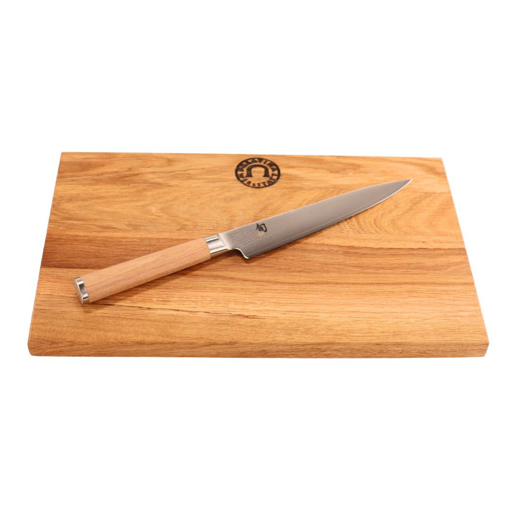 Das Kai Shun Classic White DM-0701W Allzweckmesser (15 cm VG10-Klinge, Holzgriff) liegt diagonal auf dem 30x20 cm Weinfass Küchenbrett mit heller Maserung und rundem Logo.