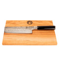 Das Kai Shun Classic Nakiri Messer Set (DM-0728, 16,5 cm, 32-lagiger Damast) mit schwarzem Griff wird mit einem 30x20 cm großen Schneidebrett aus Eichenholz geliefert, das ein dunkles, kreisförmiges Logo in der oberen Mitte trägt.