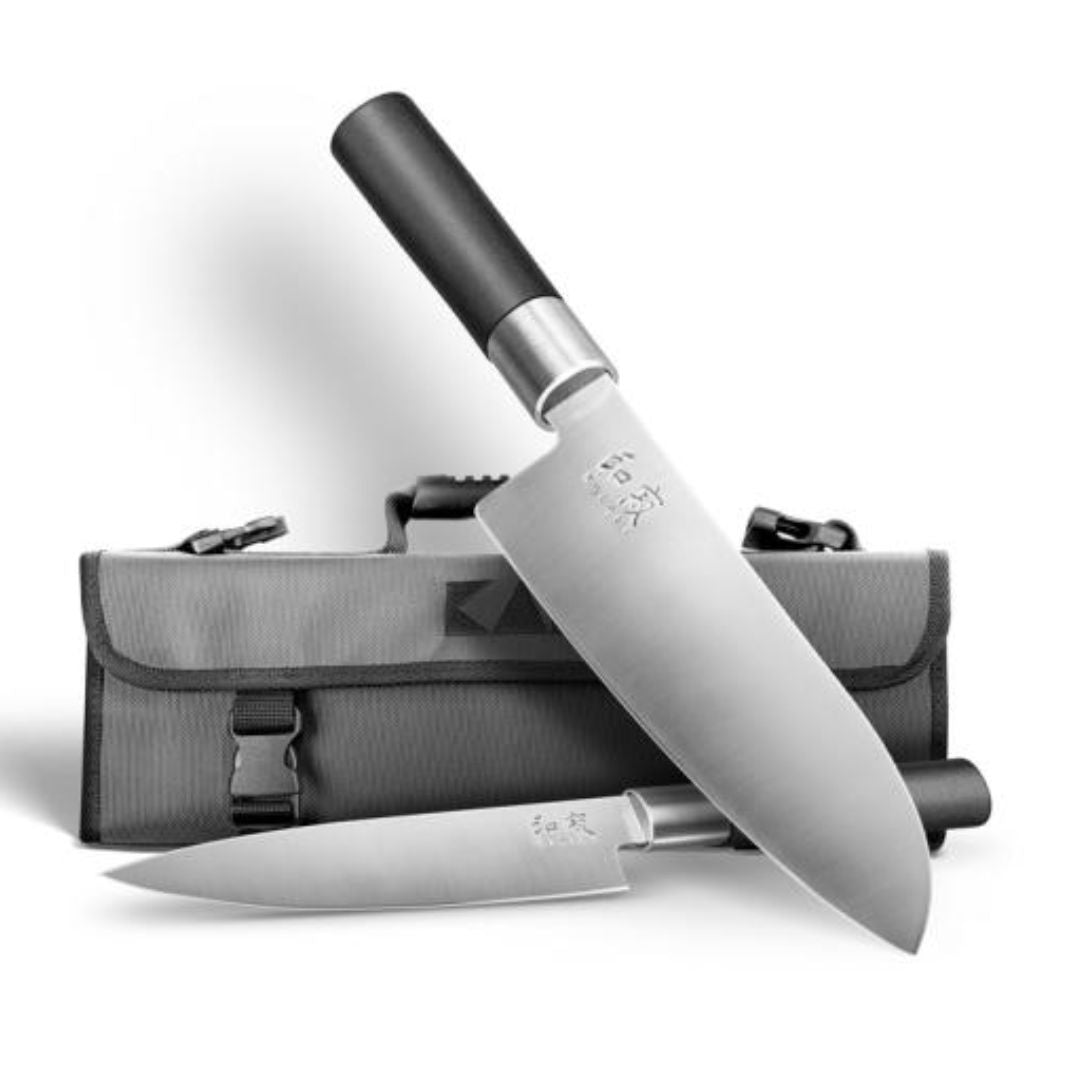 Das KAI Wasabi Black Set: Santoku, Allzweckmesser + Messertasche "THE MAGIC KAI WISHLIST 2025" wird mit einem Messer hochkant auf der grauen Tasche und dem anderen flach davor liegend präsentiert, beide mit schwarzen Griffen.