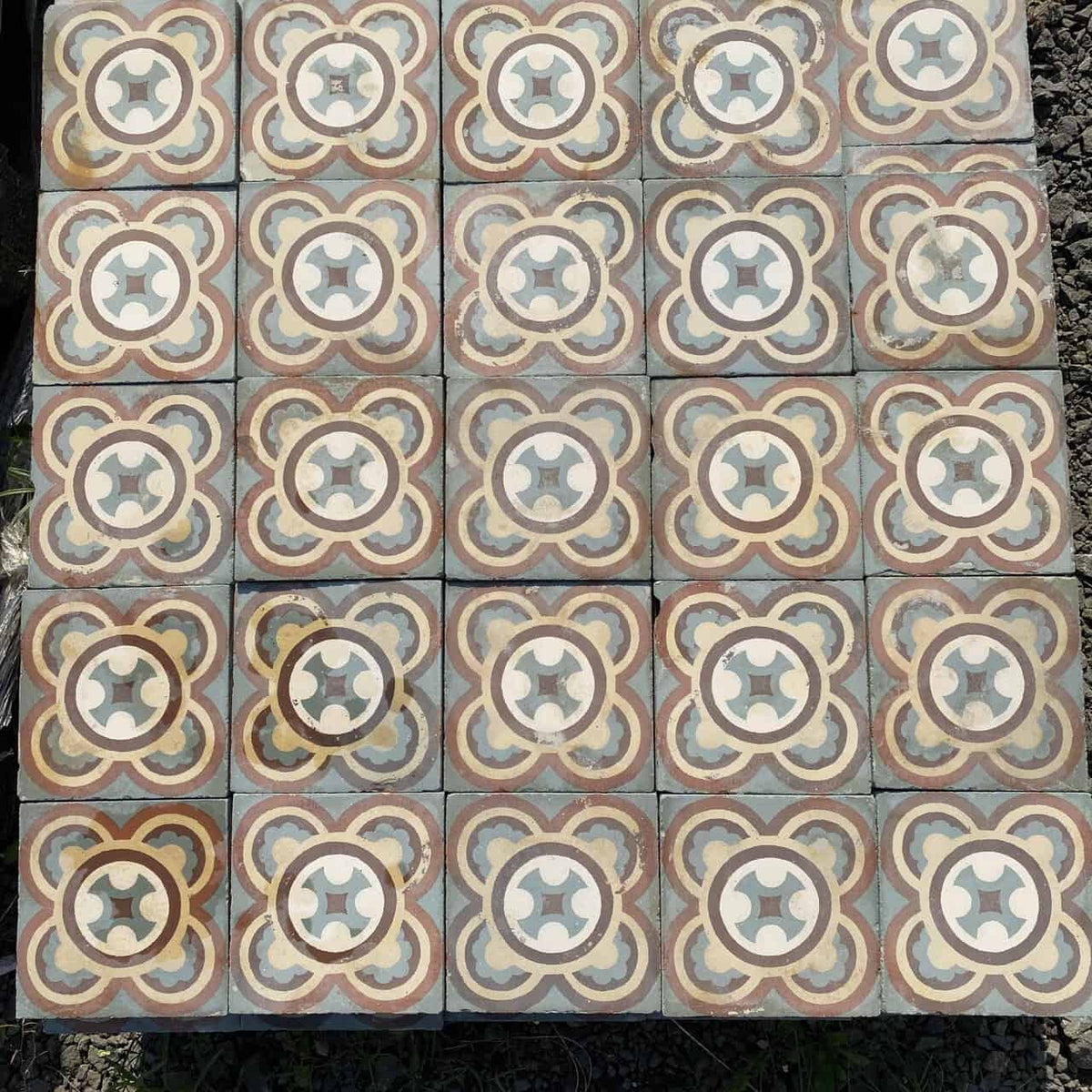 Ein Raster aus 20 quadratischen Fliesen des Typs Historische Gründerzeitfliesen, jede davon 16,5 x 16,5 cm groß, zeigt ein sich wiederholendes geometrisches Muster mit ineinandergreifenden Kreisen und Blumenmotiven in Beige-, Braun- und Hellblautönen. Diese komplexen und symmetrischen Designs spiegeln den Charme historischer Fliesen auf der gesamten Fläche wider, die etwa 5,5 Quadratmeter bedeckt.