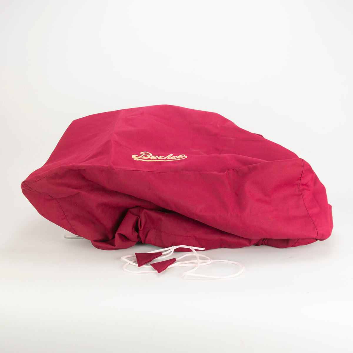 Eine zerknitterte, kastanienbraune Stofftasche mit weißen Kordeln und aufgesticktem Text „Dexter“ in Weiß. Die Tasche ist ideal zur Aufbewahrung Ihres Berkel Home Line 200 Zubehörsets, Messerabnehmer, Schleifaufsatz, Abdeckung + Poliertuch, und hat ein offenes Ende und Kordeln, die vor einem schlichten weißen Hintergrund sichtbar sind.