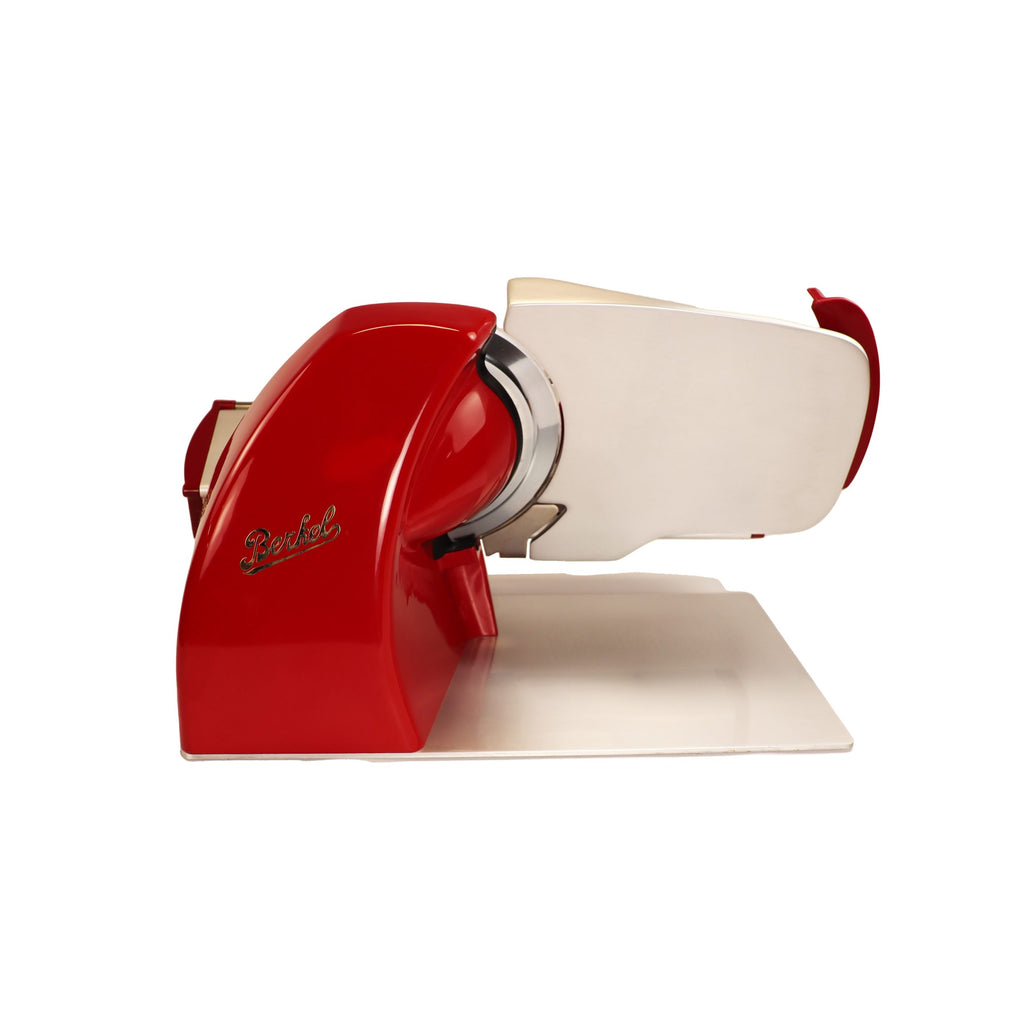 Eine rote Berkel Home Line 200 Plus Aufschnittmaschine, neues Modell mit Unikat-Schneidebrett & Wellenschliff-Bausatz für Brot, steht im Retro-Design auf weißer Fläche. Ihr glänzendes Gehäuse und die runde Klinge strahlen zeitlose Eleganz aus.