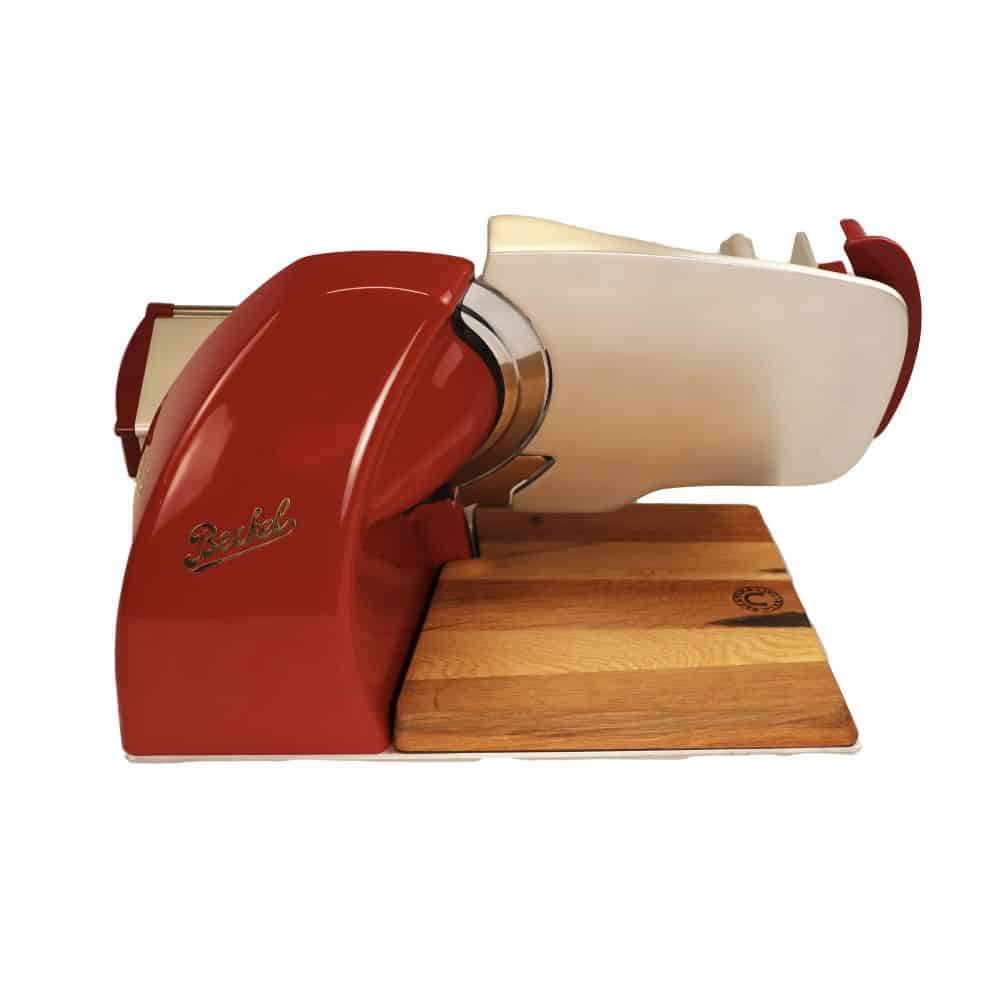 Eine Berkel Home Line 200 Plus Rot, Aufschnittmaschine - Neues Modell - Schneidemaschine in Rot und Weiß steht auf einem 100 % handgefertigten Schneidebrett Unikat. Die Maschine verfügt über ein elegantes Retro-Design mit einer teilweise sichtbaren glänzenden Metallklinge.
