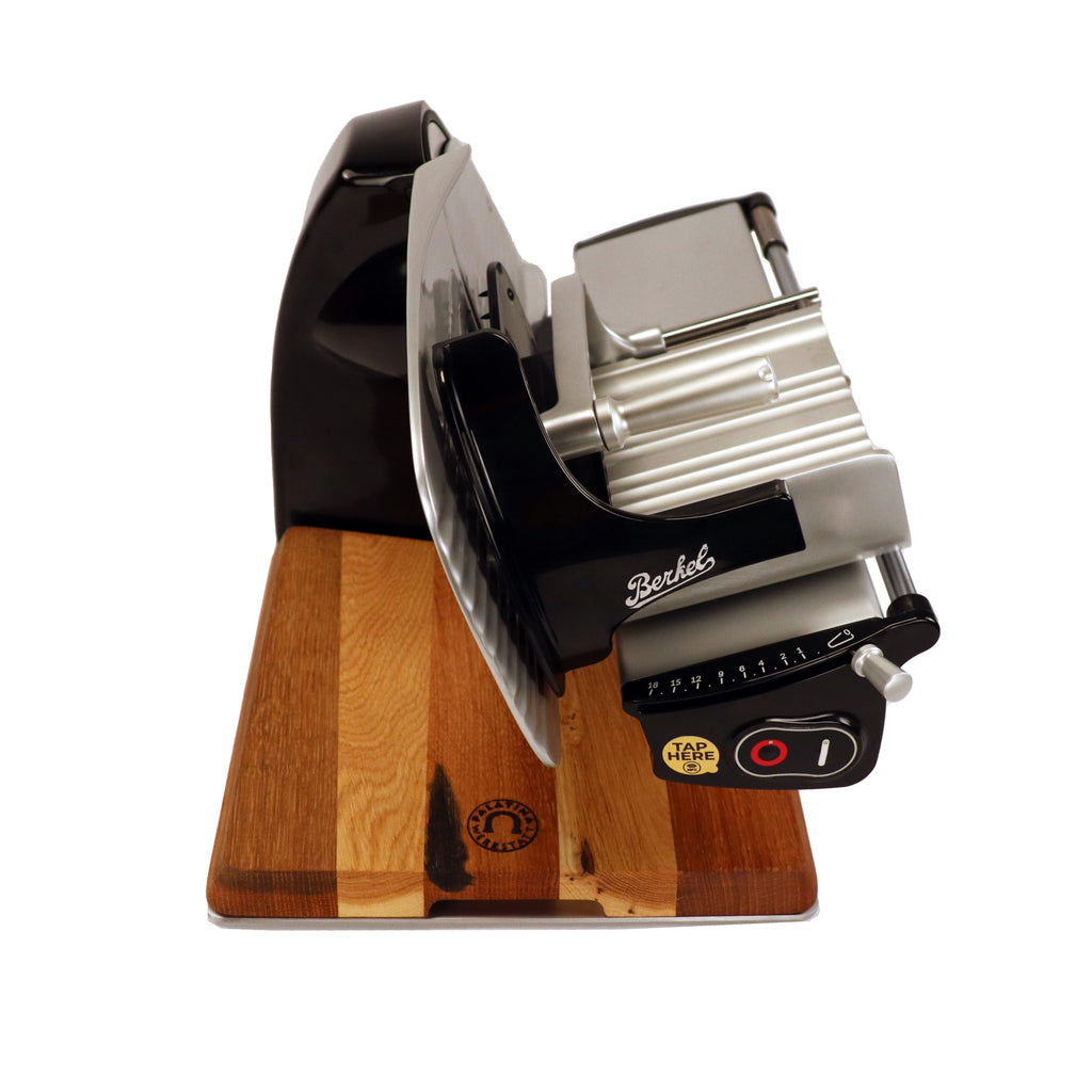 A Berkel Home Line 200 Plus schwarz Aufschnittmaschine, neues Modell, steht auf einem handgefertigten Unikat-Schneidebrett und verfügt über einen Wellenschliff-Bausatz für Brot.