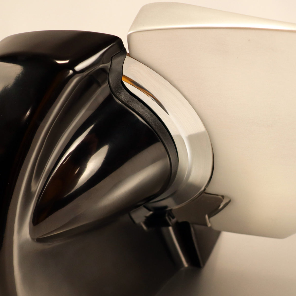 Eine Nahaufnahme der Berkel Home Line 200 Plus schwarz Aufschnittmaschine, dem neuen Modell mit handgefertigtem Unikat-Schneidebrett und Wellenschliff-Bausatz für Brot, zeigt das elegante schwarz-silberne Design mit glänzenden Metall- und Kunststoffelementen.