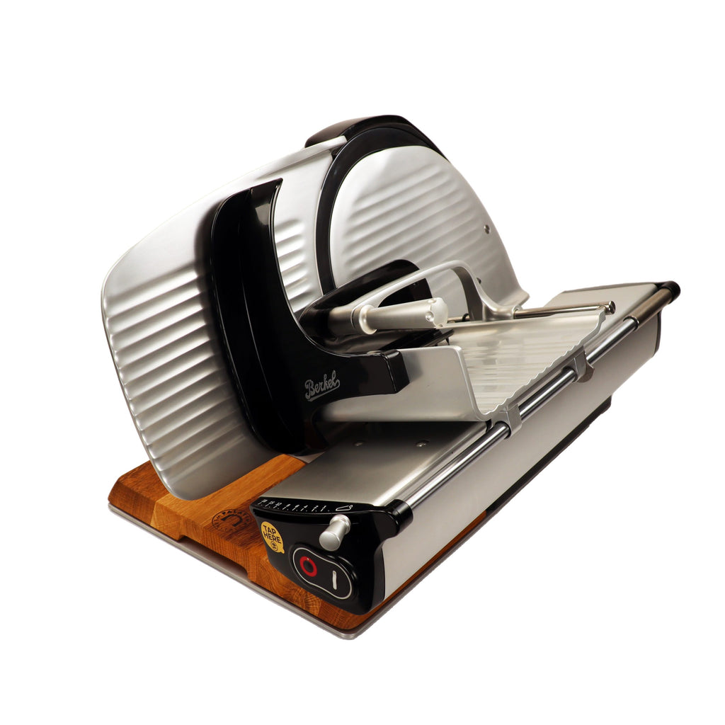 Die Berkel Home Line 250 Plus rot ist eine moderne Aufschnittmaschine, neues Modell, mit einem handgefertigten, einzigartigen Schneidebrett und einem gezackten Messersatz für Brot, isoliert auf weiß dargestellt.