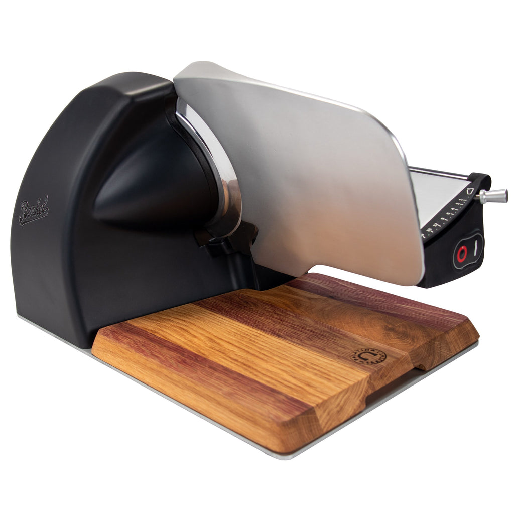 Die Berkel Home Line 200 Plus schwarz matt - Aufschnittmaschine neues Modell mit handgefertigtem Unikat-Schneidebrett & Wellenschliff-Bausatz für Brot besticht durch ihr rundes Messer und den eleganten Bedienknopf auf dem Holzbrett.