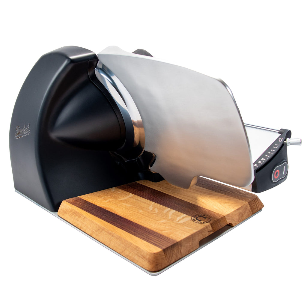 Die Berkel Home Line 250 Plus in schwarz matt - das neue Modell der Aufschnittmaschine - steht auf einem handgefertigten Unikat-Schneidebrett mit Wellenschliff-Bausatz für Brot und besticht durch ihr modernes, elegantes Design.
