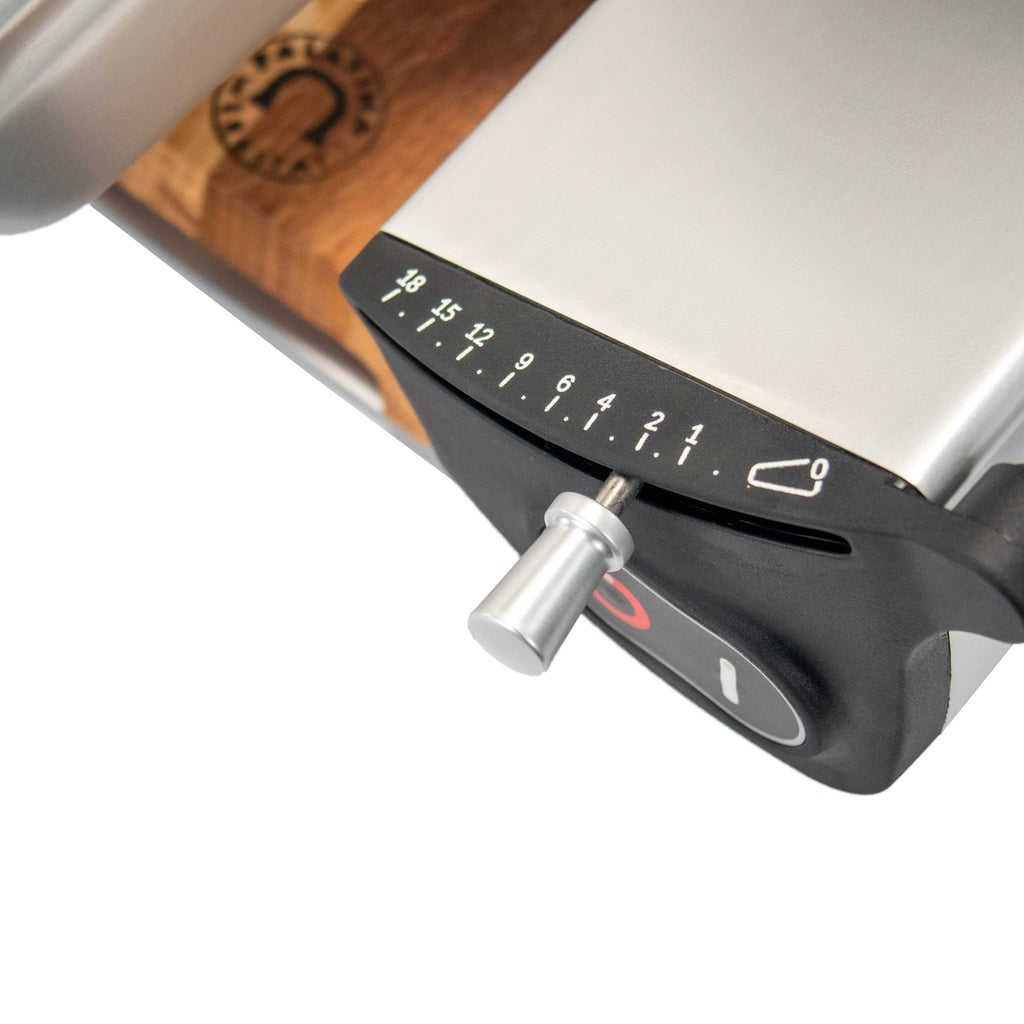 Nahaufnahme der Berkel Home Line 250 Plus Schwarz MATT Aufschnittmaschine - Neues Modell, mit nummeriertem Einstellrad (1-18) und einzigartigem, handgefertigtem Schneidebrett auf Holzoberfläche; teilweise sichtbares Logo im Hintergrund.