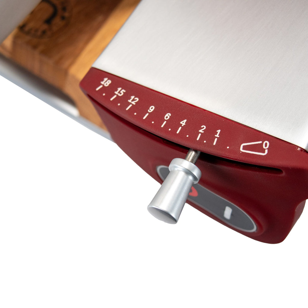 Nahaufnahme des rot-silbernen Einstellrads der Berkel Home Line 250 Plus Rot MATT Aufschnittmaschine, mit Einstellungen von 0 bis 18 und einem Metallgriff; inklusive neuem Schneidemodell und einzigartigem handgefertigtem Schneidebrett.