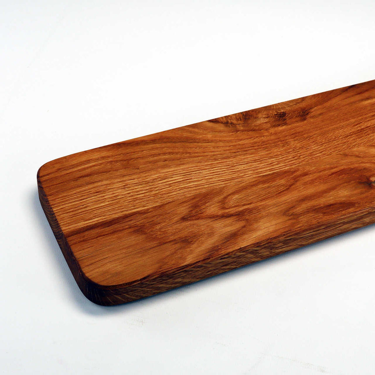 Eine Nahaufnahme eines rechteckigen, von der Palatina Werkstatt handgefertigten Baguettebretts, Käsebrett aus altem Weinfassholz mit abgerundeten Kanten. Die Holzmaserung aus Weinfassholz ist deutlich sichtbar und weist verschiedene Brauntöne auf. Der Hintergrund ist weiß und bildet einen starken Kontrast zur satten Textur des Schneidebretts.