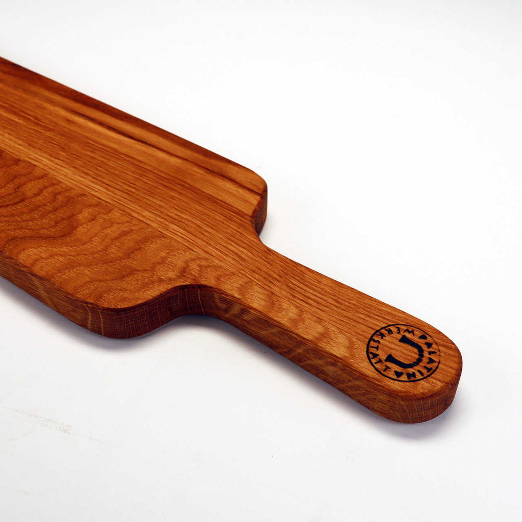Dieses wunderschön gefertigte Palatina Werkstatt Käsebrett ist ein handgefertigtes Baguettebrett aus wiederverwertetem Weinfassholz und verfügt über einen langen Griff. Das Logo „ATLANTA WOOD COMPANY“ ist nahe dem Ende des Griffs eingraviert und es verfügt über eine glatte, polierte Oberfläche mit sichtbaren Holzmaserungen.