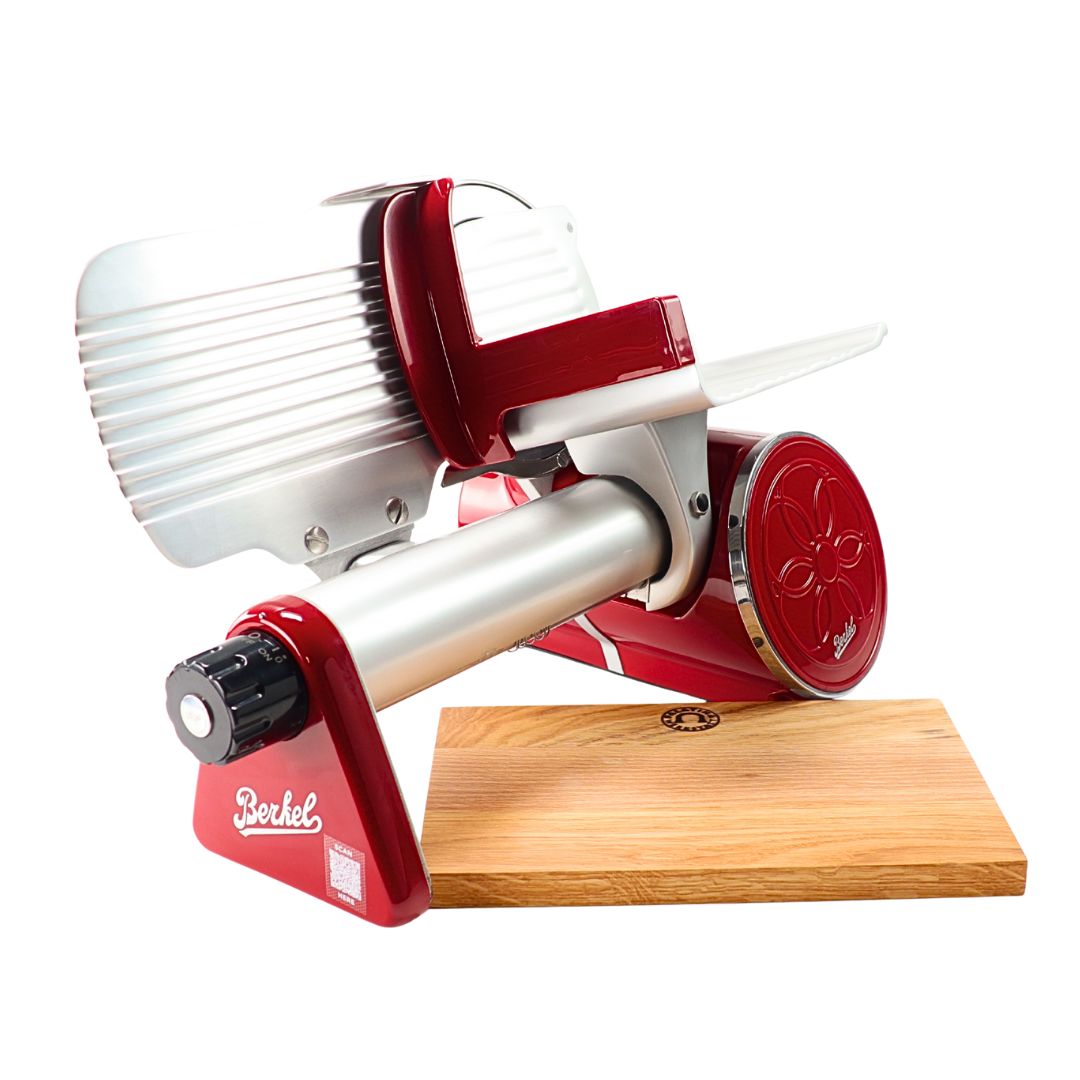 A Berkel Icon Line 170 in rot steht auf einem handgefertigten Einlegebrett aus Eichenholz (30x20 cm). Der Allesschneider hat eine große runde Klinge, einen Griff und einen geriffelten Metallschutz für die Lebensmittelablage.