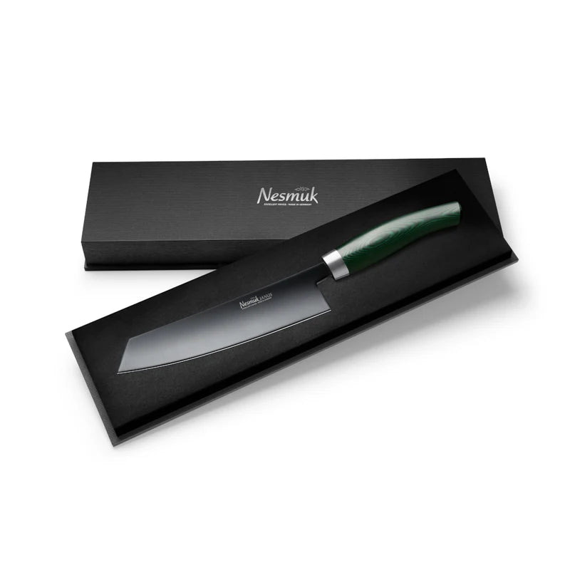 Das Nesmuk Janus Kochmesser 180 mm ist ein hochwertiges Kochmesser mit einer glatten Klinge und verschiedenen Griffmaterialien zur Auswahl. Präsentiert in einer schwarzen, rechteckigen Geschenkbox mit dem Markennamen „Nesmük“ auf dem Deckel, unterstreicht sein minimalistisches Design seine luxuriöse Ausstrahlung.