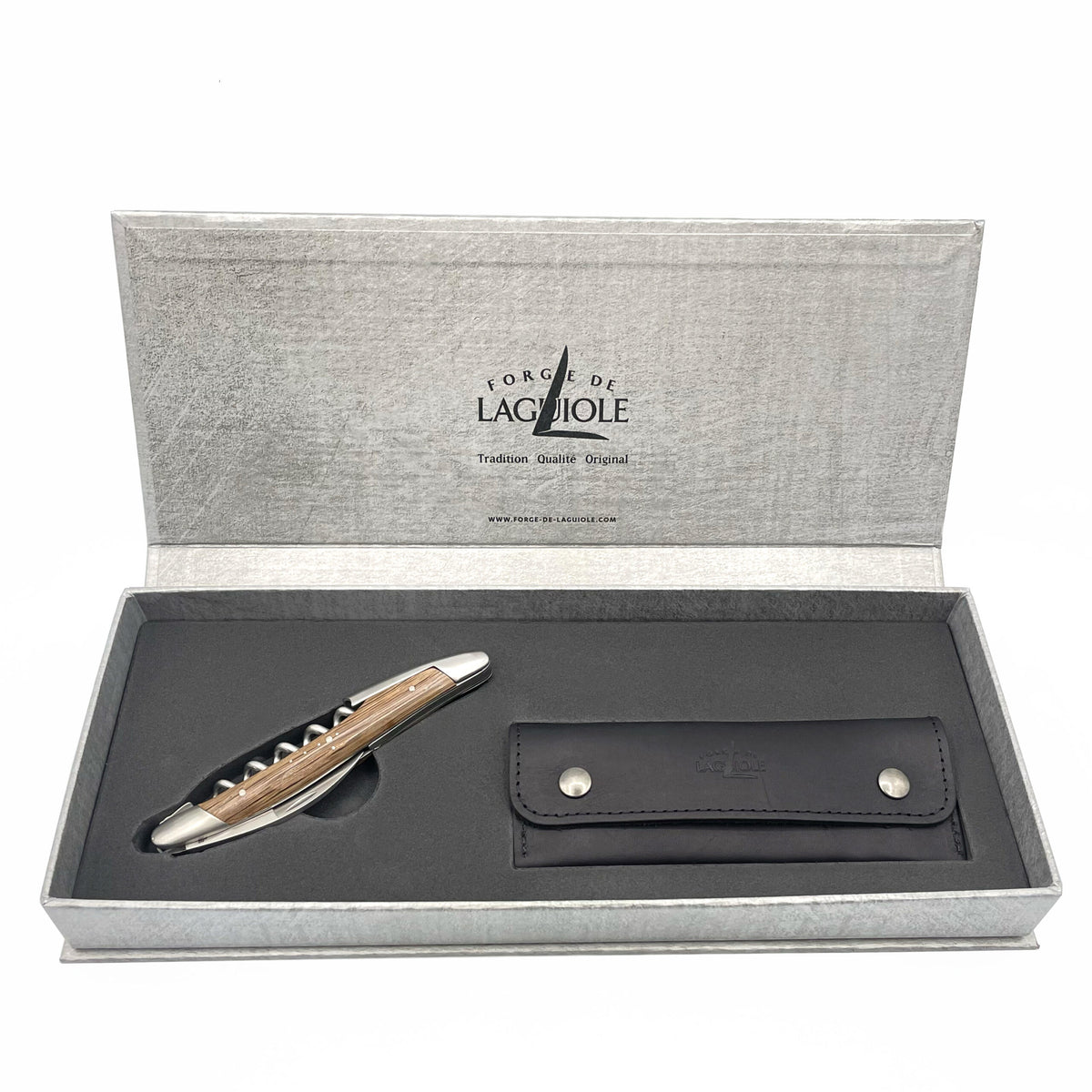 Ein Set mit dem Kellnermesser Sommelier von Forge De Laguiole, komplett mit einem Klapptaschenmesser mit einem Holzgriff aus Mooreiche und Edelstahlakzenten sowie einer schwarzen Lederscheide mit Knopfverschluss. Auf der Innenseite sind stolz das Markenlogo und der Name „Forge de Laguiole“ sowie „Tradition“ und „Originalqualität“ zu sehen. Ideal für jeden Sommelier, der Wert auf hervorragende Handwerkskunst legt.