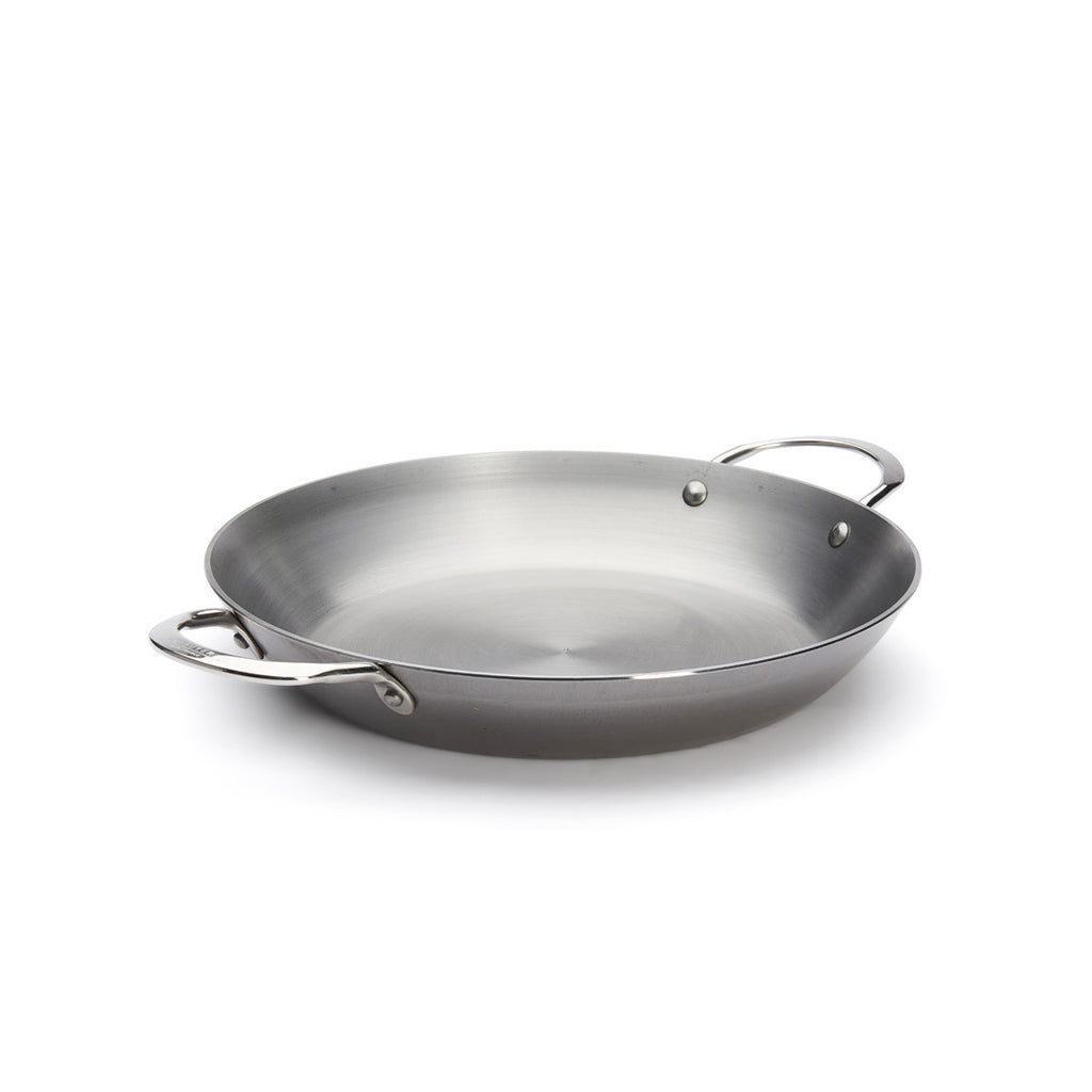 Die De Buyer Paella-Pfanne Mineral B, 32 cm, mit zwei seitlichen Griffen, steht auf einem weißen Untergrund. Diese Pfanne aus Kohlenstoffstahl hat eine breite, flache Form und eine glatte Oberfläche, die ideal für die Zubereitung authentischer Paella-Gerichte ist.