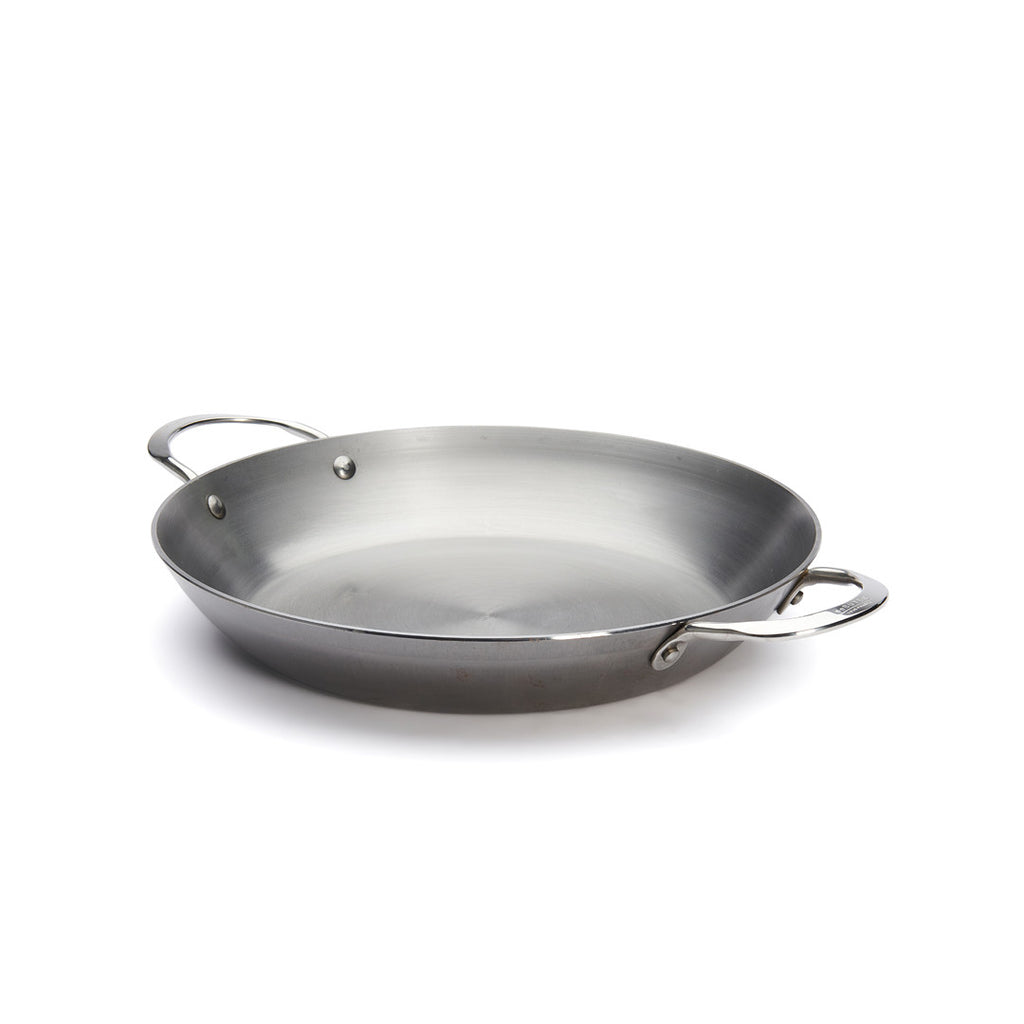 Die De Buyer Paella-Pfanne Mineral B, 32 cm Dm, ist eine große runde Stahlpfanne mit zwei Griffen, abgeschrägten Seiten und einer glatten, glänzenden Oberfläche auf weißem Grund.