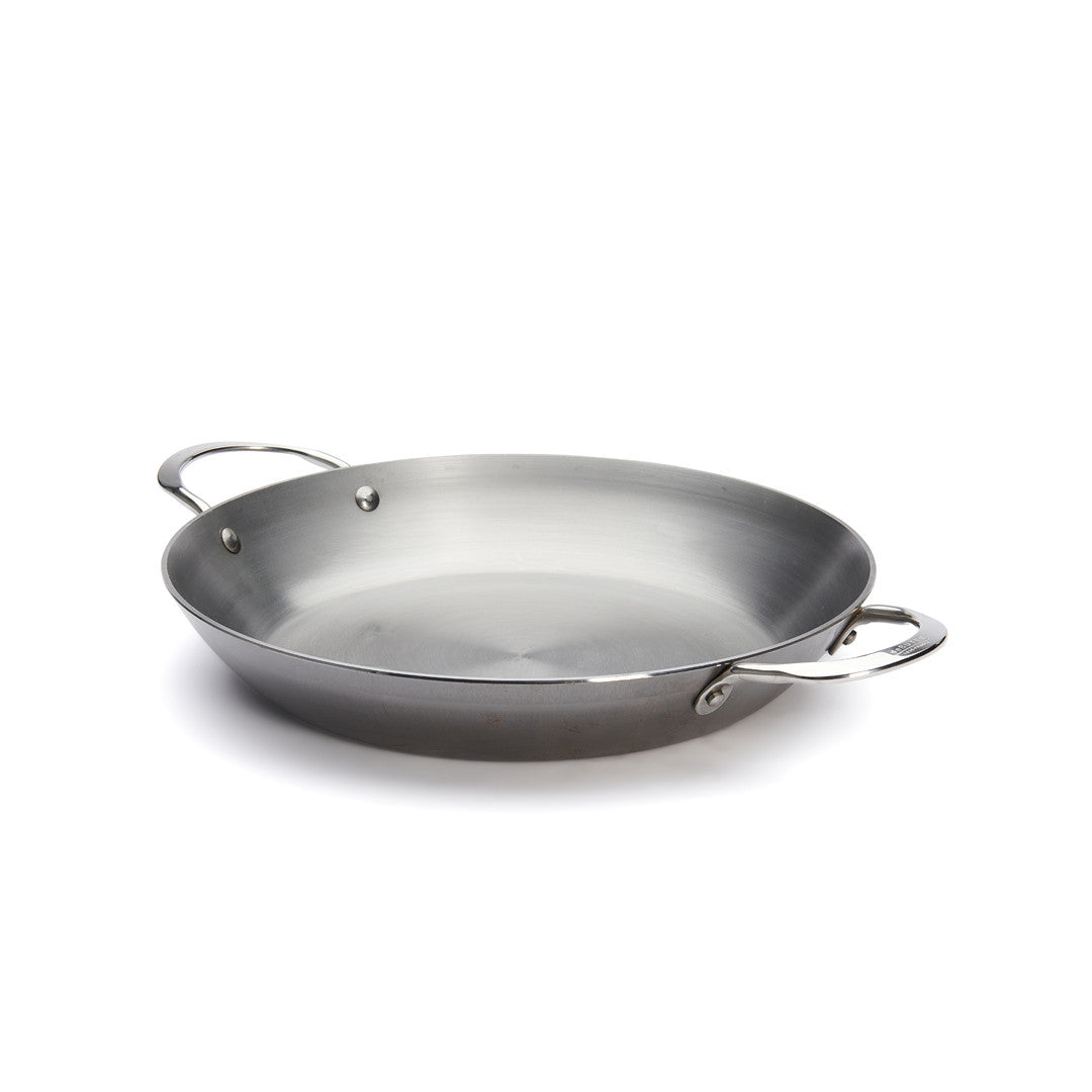 Die De Buyer Paella-Pfanne Mineral B, 32 cm Dm, ist eine große runde Stahlpfanne mit zwei Griffen, abgeschrägten Seiten und einer glatten, glänzenden Oberfläche auf weißem Grund.
