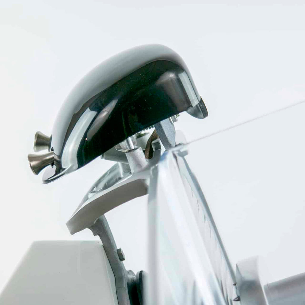Nahaufnahme eines eleganten elektrischen Haarschneiders. Die Metallklingen und der verstellbare Kunststoffschutz des Haarschneiders sind deutlich zu erkennen und erinnern an die Präzision einer Berkel Red Line 250 Weiß, Original Profi-Aufschnittmaschine mit 25 cm Klingendurchmesser und Fassholz-Schneidebrett. Vor einem sauberen, weißen Hintergrund wirkt das Gerät modern und gut gepflegt.