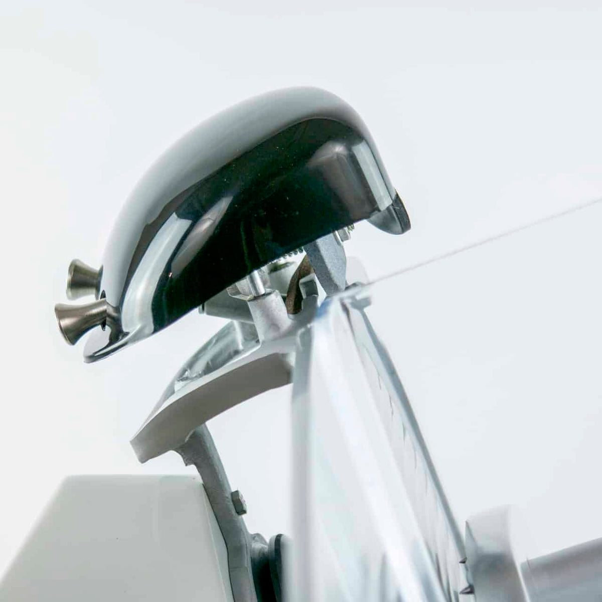 Nahaufnahme eines eleganten elektrischen Haarschneiders. Die Metallklingen und der verstellbare Kunststoffschutz des Haarschneiders sind deutlich zu erkennen und erinnern an die Präzision einer Berkel Red Line 250 Weiß, Original Profi-Aufschnittmaschine mit 25 cm Klingendurchmesser und Fassholz-Schneidebrett. Vor einem sauberen, weißen Hintergrund wirkt das Gerät modern und gut gepflegt.