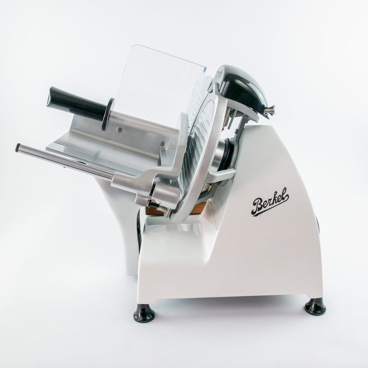 Eine Seitenansicht der Berkel Red Line 250 Weiss, Original Profi-Aufschnittmaschine ist vor einem schlichten weißen Hintergrund zu sehen. Der weiß-silberne Allesschneider verfügt über ein großes rundes Messer mit einem Messerdurchmesser von 25 cm, ein Einstellrad für die Schnittstärke und einen Griff zur Bedienung. Das Berkel-Logo ist deutlich sichtbar an der Seite angebracht und er verfügt über ein Einlegebrett aus Fassholz.