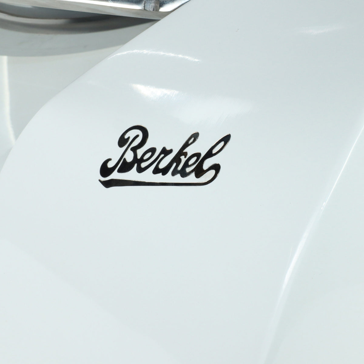 Nahaufnahme einer weißen Oberfläche, die mit „Berkel“ in schwarzer, kursiver Schrift verziert ist, was die Verbindung zur Berkel Red Line Weiß 300 mm Original Profi-Aufschnittmaschine + Weinfass Einlegebrett betont. Die glatte und glänzende Oberfläche reflektiert das Licht und lenkt den Fokus ausschließlich auf den Markennamen, während andere erkennbare Details weggelassen werden.
