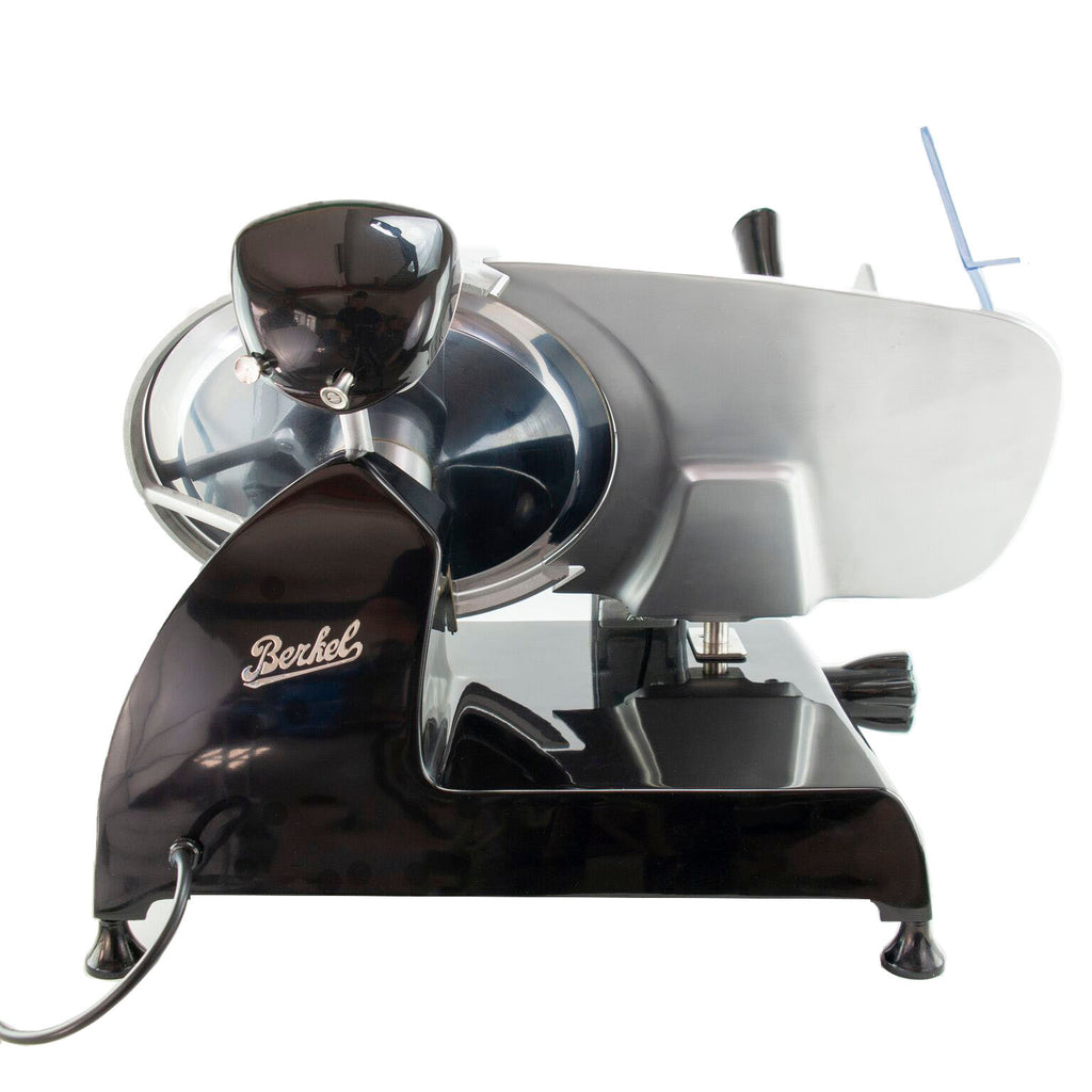 Ein Bild zeigt die Berkel Red Line 300 Schwarz, Original Profi-Aufschnittmaschine im Vintage-Stil mit schwarzem und metallischem Finish. Diese Fleischschneidemaschine verfügt über ein rundes Messer mit einem Messerdurchmesser von 300 mm, einen einstellbaren Dickenknopf und ein Netzkabel, das aus der Basis herausragt. Außerdem ist ein Fassholz-Einlegebrett enthalten.
