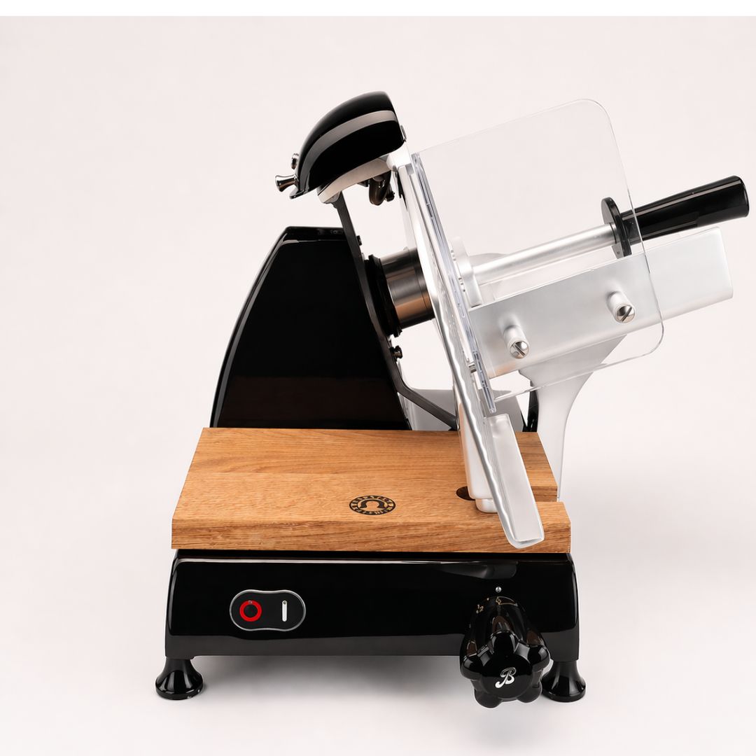 Eine Berkel Red Line 250 Schwarz Profi-Aufschnittmaschine mit 25 cm Klinge, schwarzem Sockel, hölzerner Schneidefläche und durchsichtigem Schutzgitter ist vor einem schlichten weißen Hintergrund abgebildet.